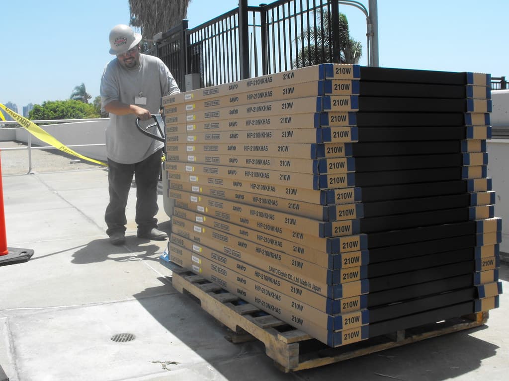 Palletized boxed solar panels being moved during a solar equipment handling project
