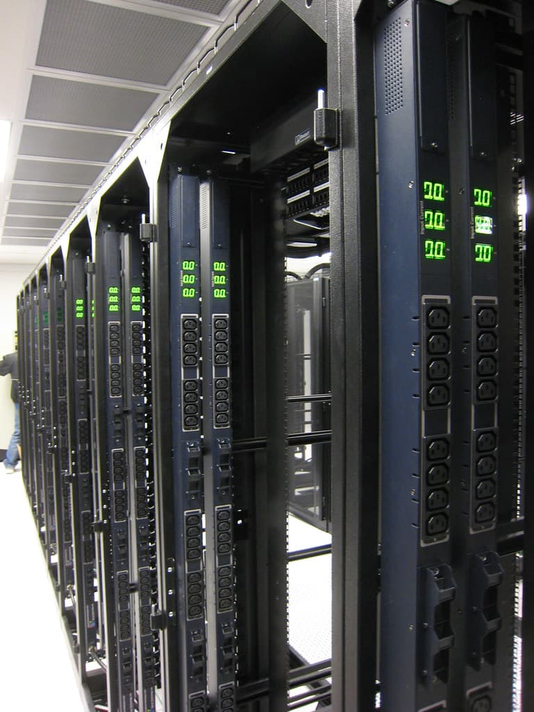 Rows of server racks and powered infrastructure inside a data center environment