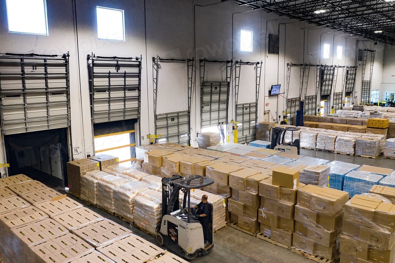 Large warehouse inventory with palletized loads and forklift activity across multiple aisles