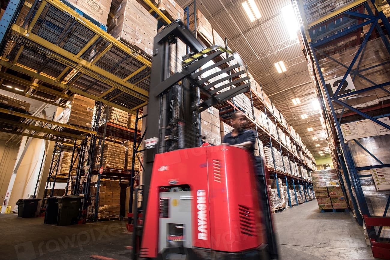 Forklift moving through a warehouse aisle during a coordinated surplus logistics operation